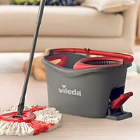 a vileda mop an bucket in a living room with a couch in the background